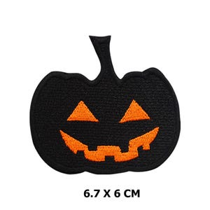 Könnte beinhalten: Schwarzer Filz-Halloween-Kürbis-Patch mit einem orangefarbenen gestickten Kürbisgesicht. 6,7 x 6 cm.
