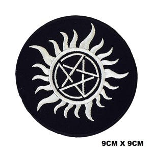 May include: Black and white embroidered patch with a pentagram inside a circle with a sunburst design. The patch is 9 inches by 9 inches.
