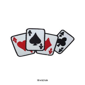 May include: Four playing cards, an ace of spades, an ace of hearts, an ace of diamonds, and an ace of clubs, are arranged in a cluster. The cards are white with black and red embroidery. The cards are 10 cm by 6.3 cm.