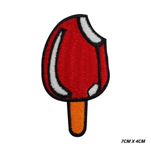 Op de afbeelding: Geborduurde patch van een rode ijslolly met een hap eruit. De ijslolly heeft witte en zwarte contouren en een oranje stok. De patch meet 7 cm x 4 cm.
