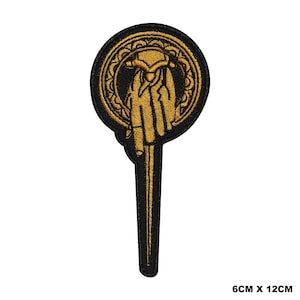 May include: A gold embroidered iron throne hand patch with a black background. The patch is 6 cm by 12 cm.