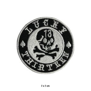 Könnte beinhalten: Schwarz-weiß gestickter Patch mit Totenkopf und Knochen, der Zahl 13 und dem Text "Lucky Thirteen".