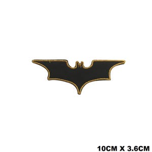May include: Black and gold embroidered iron-on patch of the Batman logo. The logo is a stylized bat silhouette with a pointed wingspan. The patch measures 10 cm by 3.6 cm.