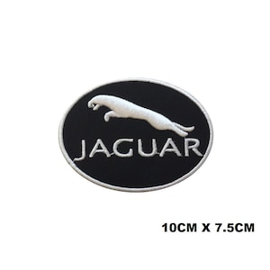 Puede incluir: Parche bordado con el logotipo de Jaguar. El parche tiene un fondo ovalado negro con un jaguar blanco saltando sobre él. La palabra "JAGUAR" está bordada en blanco. El parche mide 10 cm x 7,5 cm.
