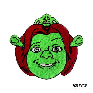 May include: Embroidered patch of a green character with red hair and a crown. The patch measures 7cm x 6cm. The character has a smiling expression and is set against a white background. Suitable for clothing or accessories.