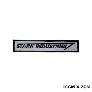 Puede incluir: Parche blanco bordado con texto negro que dice "STARK INDUSTRIES" con una línea diagonal negra a través de la palabra "INDUSTRIES". El parche mide 10 cm por 2 cm.