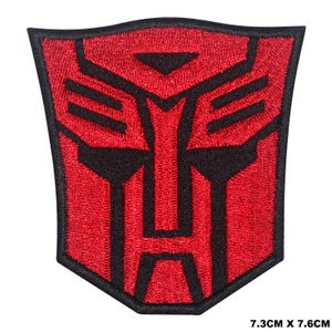 Könnte beinhalten: Roter und schwarzer gestickter Bügel-Patch mit dem Autobot-Symbol, einem stilisierten Robotergesicht. Der Patch misst 7,3 cm x 7,6 cm.