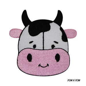 May include: Embroidered patch of a cartoon cow's face. The cow has a white face with black spots, black horns, and pink ears and muzzle. The patch measures 7cm x 7cm.