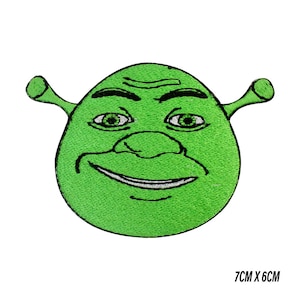 Puede incluir: Parche bordado con la cara de un ogro verde con una amplia sonrisa, ojos verdes y orejas pequeñas. El parche mide 7 cm x 6 cm. El parche es probablemente para ropa o accesorios.