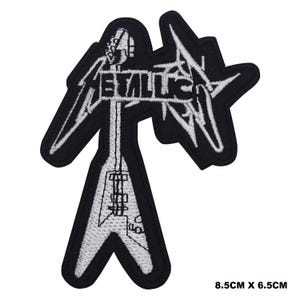 May include: Black and white embroidered iron-on patch featuring the Metallica logo with a stylized electric guitar. The patch measures 8.5 cm by 6.5 cm.