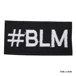 Può includere: Toppa rettangolare nera con testo ricamato bianco che recita "#BLM". La toppa misura 7 cm x 3,5 cm. Il simbolo cancelletto è seguito dalle lettere B, L e M.