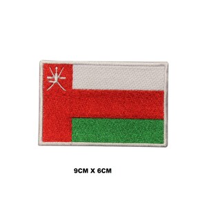 Pode incluir: Patch retangular com a bandeira de Omã. O design apresenta listras vermelhas, brancas e verdes, com um emblema branco no canto superior esquerdo. Mede 9 cm x 6 cm.