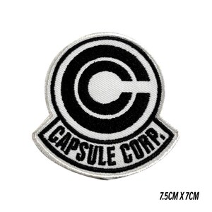 May include: A circular embroidered patch featuring a black and white design with a large letter C inside a circle and the text CAPSULE CORP. printed below. The patch measures 7.5 cm by 7 cm and has a white border with black stitching details.