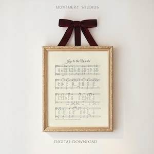 May include: A framed print of sheet music with the words "Joy to the World" in elegant script. The frame is gold-toned, and a burgundy ribbon is tied at the top for hanging. The words "Digital Download" are at the bottom.