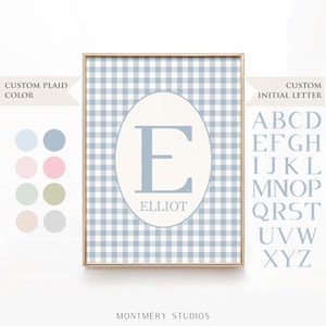 May include: A framed print featuring a blue and white gingham pattern background. A light blue letter "E" is centered within an oval, with the name "ELLIOT" below. The print offers custom plaid colors and initial letters.