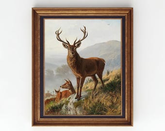 May include: A framed vintage art print featuring a majestic stag with large antlers standing on a rocky hillside, with two other deer in the background. The artwork is set against a backdrop of rolling hills and a cloudy sky. The frame is a dark brown color.