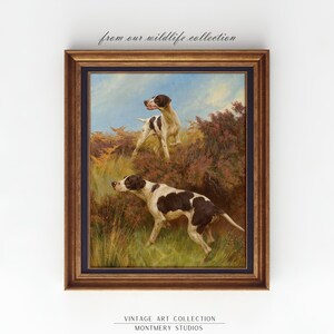 May include: A vintage oil painting of two brown and white hunting dogs in a field. The dogs are standing in a field of tall grass and wildflowers. The painting is framed in a dark wood frame.