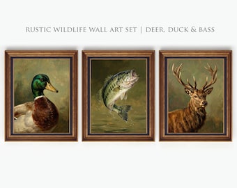 Könnte beinhalten: Set aus drei gerahmten rustikalen Wildtier-Kunstdrucken. Die Drucke zeigen eine Ente, einen springenden Bassfisch und einen Hirsch mit Geweih. Die Rahmen sind braun mit einem dunkelblauen Rand. Der Text "RUSTIC WILDLIFE WALL ART SET | DEER, DUCK & BASS" steht oben.