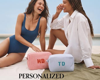 May include: Two rectangular zippered pouches featuring a fine pinstripe pattern. One pouch is red and white with the orange embroidered initials HB, while the other is blue and white with the teal embroidered initials TD on the front surface.