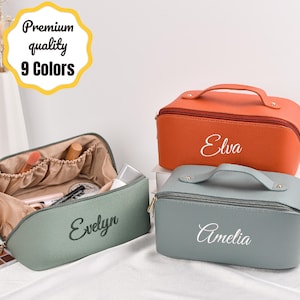 Puede incluir: Tres neceseres en naranja, verde salvia y gris. La bolsa verde salvia está abierta, revelando maquillaje en su interior. Las bolsas naranja y gris están cerradas, cada una con un asa y un nombre en escritura blanca. El texto dice "Premium quality 9 Colors."