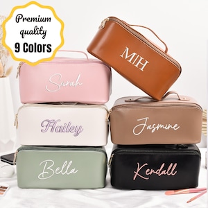 Puede incluir: Una colección de neceseres rectangulares en varios colores, como rosa, marrón y negro. Cada neceser tiene una cremallera dorada y un asa. Los neceseres están personalizados con nombres o iniciales en cursiva. La imagen también incluye el texto "Premium quality 9 Colors."