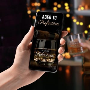 May include: A smartphone displaying a birthday invitation with a dark background and gold text. The invitation reads "Aged to Perfection" and "Please join us to celebrate Sebastian's 45th Birthday". The image also features a glass of whisky and a cigar.