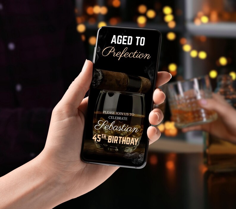 May include: A smartphone displaying a birthday invitation with a dark background and gold text. The invitation reads "Aged to Perfection" and "Please join us to celebrate Sebastian's 45th Birthday". The image also features a glass of whisky and a cigar.