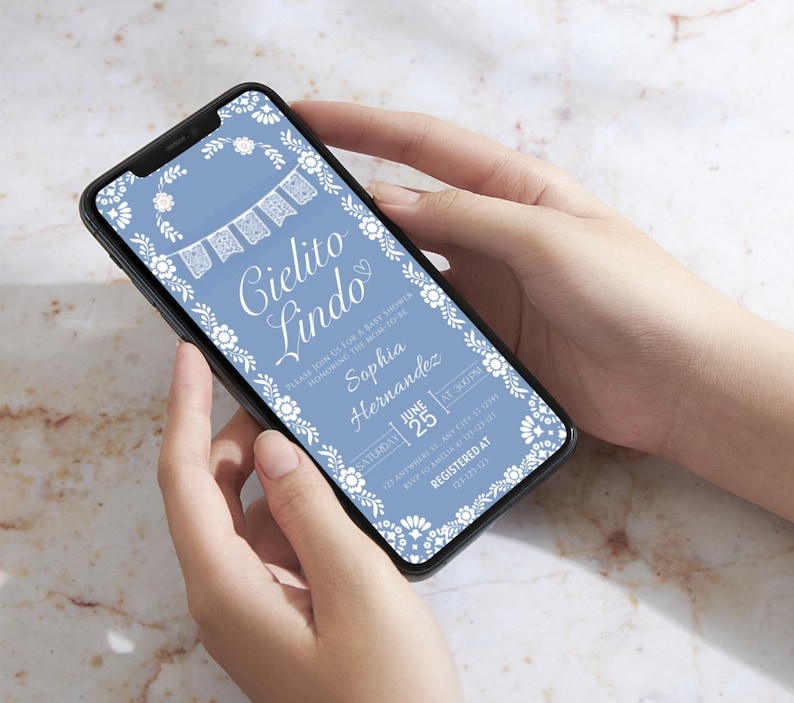 May include: A light blue baby shower invitation displayed on a smartphone. The invitation features white floral and banner designs, with the words "Cielito Lindo" in elegant script. Details include the name Sophia Hernandez, date, and time.