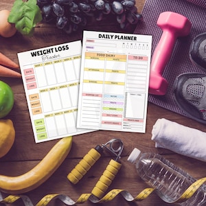 May include: A fitness-themed still life featuring a weight loss tracker and daily planner. A pink dumbbell, running shoes, and a water bottle are also present. Fresh fruit and vegetables, along with hand grips and a measuring tape, complete the scene.