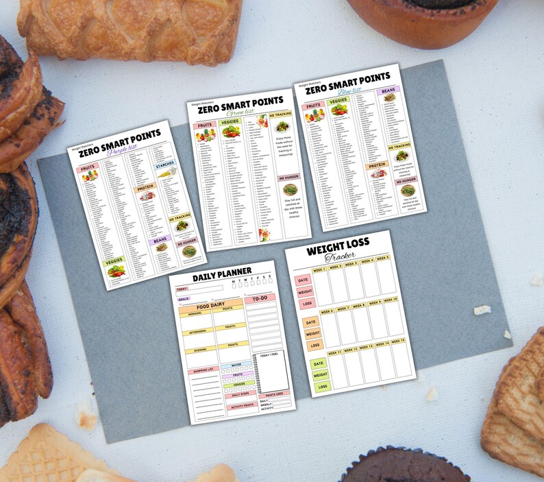 May include: A collection of printed planner sheets, including a weight loss tracker, daily planner, and several "Zero Smart Points" lists. The sheets are white with colorful accents and text. Baked goods surround the sheets.