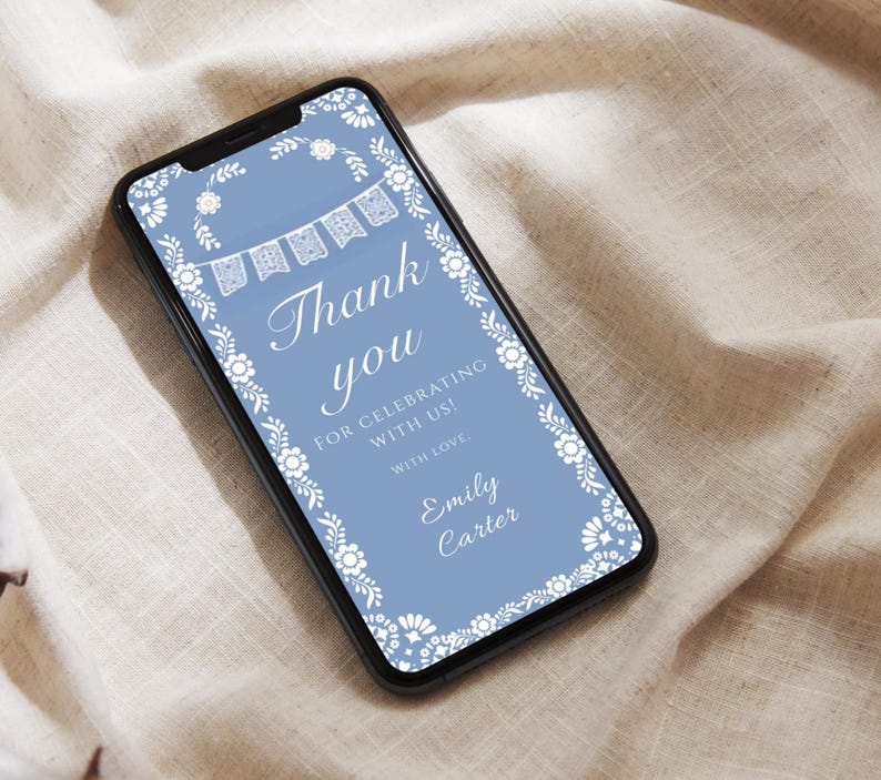 May include: A smartphone screen shows a digital invitation with a pale blue backdrop. The design includes white floral and banner motifs, with the words "Thank you" in a graceful script. The text "For celebrating with us! With love, Emily Carter" is also present.