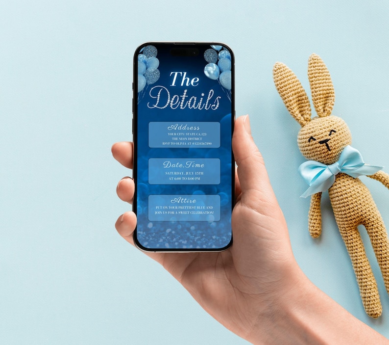 May include: A blue and silver smartphone screen displaying a baby shower invitation with the text "The Details" and sections for address, date, time, and attire.