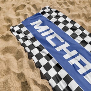 May include: A black and white checkered beach towel with a blue stripe and the name "MICHAEL" printed in white.