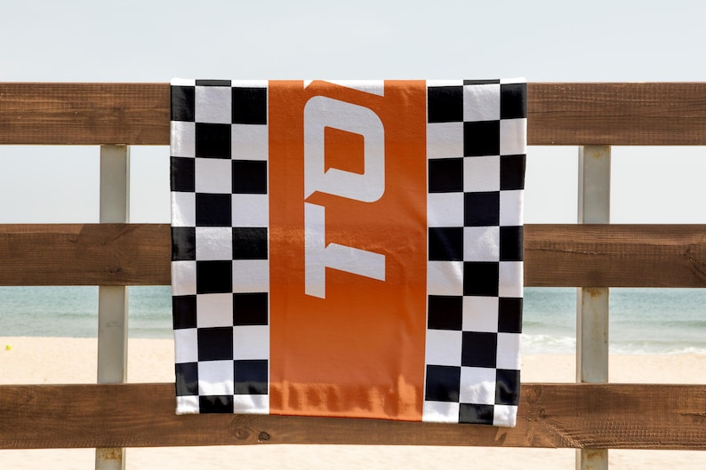May include: A black and white checkered beach towel with an orange stripe and the word "TOTO" printed in white.