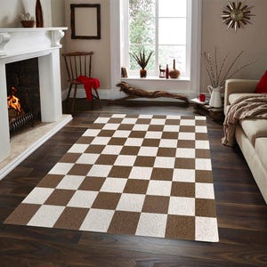 May include: A brown and white checkered rug in a living room setting. The rug is rectangular and covers a portion of the dark wood floor. The room features a fireplace, a sofa, and a window with natural light.