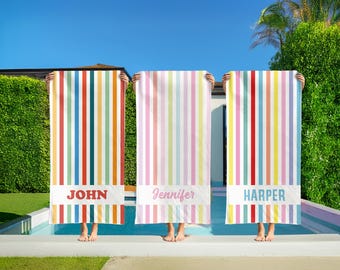 May include: Three colorful striped beach towels with names "John", "Jennifer", and "Harper" printed on them. The towels are held up by people standing in front of a swimming pool.