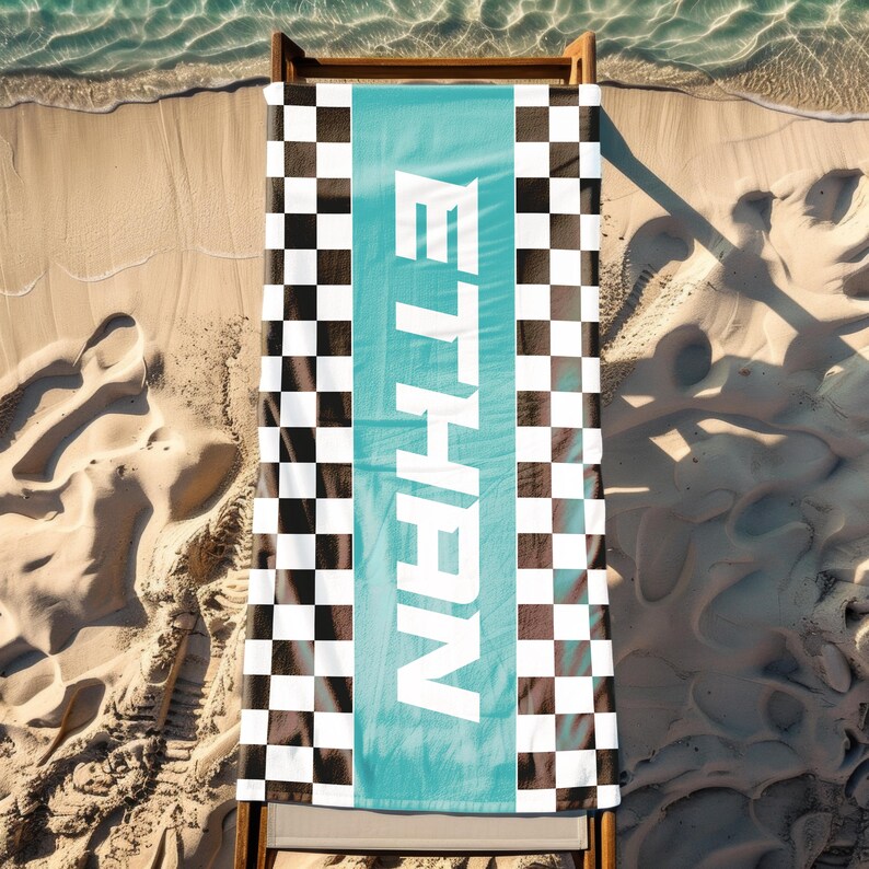 May include: A beach towel with a black and white checkered pattern and a turquoise blue stripe with the word "ETHAN" in white letters.