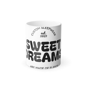 May include: White ceramic mug with the text "SWEET DREAMS" in black, rounded letters. The words "CUSTOM SLEEPWEAR est. 2021" are printed above the main text, and "ARE MADE OF FLEECE" is printed below.