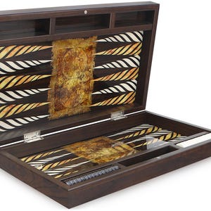 Könnte beinhalten: Ein Backgammon-Set aus Holz mit brauner Oberfläche und einer gold-weißen Spielfläche. Das Set ist geöffnet und die Spielfläche ist sichtbar. Das Set enthält ein Fach zur Aufbewahrung der Würfel und ein Fach für die Spielsteine.