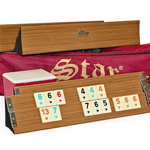 Puede incluir: Un juego de Rummikub de madera con una funda de transporte roja, un estante para fichas y fichas con números y símbolos. Las fichas están dispuestas en un patrón en el estante.
