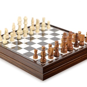 Könnte beinhalten: Ein Schachspiel aus Holz mit braunen und weißen Figuren auf einem schwarz-weiß karierten Brett. Das Brett ist geschlossen und die Figuren sind in ihren Startpositionen angeordnet.