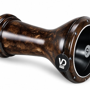 Pode incluir: Um tambor darbuka em forma de taça com um acabamento marmoreado em castanho escuro e preto. O tambor tem uma cabeça circular larga com uma pele sintética preta, um aro prateado fixado por parafusos metálicos e uma etiqueta preta redonda.