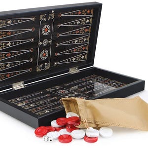 Może przedstawiać: Czarny drewniany zestaw do gry w backgammona z ozdobnym intarsjowanym wzorem. Zestaw zawiera drewnianą planszę, kostki do gry i czerwone i białe pionki. Plansza jest otwarta, a pionki znajdują się w brązowym worku z tkaniny.