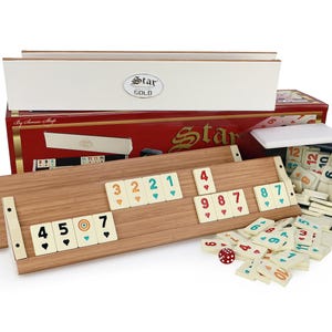 Könnte beinhalten: Ein Rummikub-Spiel aus Holz mit einer rot-weißen Schachtel, einem weißen Deckel und einem schwarzen Tablett. Das Spiel enthält einen Satz von Spielsteinen mit Zahlen und Farben sowie zwei Holzgestelle zum Halten der Spielsteine. Das Spiel enthält auch einen Satz Würfel.