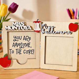 May include: A wooden photo frame with the text "YOU ARE AWESOME, TO THE CORE!" and the names "Mrs. Montoya" and "Miss Balderrama". The frame is decorated with red apple accents and is designed to hold two photos.