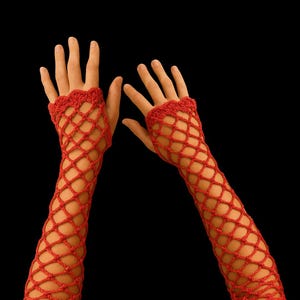 Pode incluir: Um par de aquecedores de braço de crochê vermelho com tecido aberto. Os aquecedores de braço apresentam um padrão de rede em forma de diamante e uma borda ondulada no pulso e na parte superior do braço. O fundo é preto sólido.