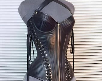 May include: Black leather corset with a halter neck and zip closure. The corset is displayed on a grey mannequin and features lace-up detailing on the sides. The corset has a structured, bustier-style design.