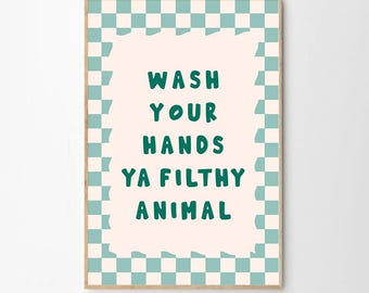 Puede incluir: Una impresión artística enmarcada con el texto "WASH YOUR HANDS YA FILTHY ANIMAL" en verde, sobre un fondo rosa claro. El borde presenta un patrón de cuadros en azul claro y blanco, con un marco de madera.