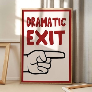 Puede incluir: Un cuadro enmarcado con las palabras "DRAMATIC EXIT" en rojo, sobre una ilustración en blanco y negro de una mano que apunta hacia la derecha. El cuadro tiene un borde rojo y un marco de madera natural.