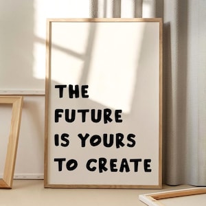 Könnte beinhalten: Ein gerahmter Druck mit dem Text "THE FUTURE IS YOURS TO CREATE" in fetten schwarzen Buchstaben. Der Druck hat einen cremefarbenen Hintergrund und ist in einem hellbraunen Holzrahmen gefasst. Das Bild ist gut beleuchtet, mit weichen Schatten.